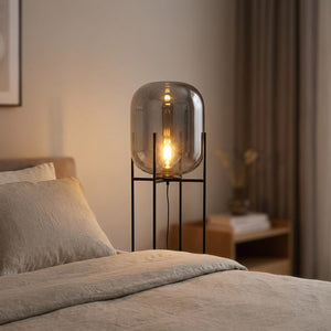 Lampadaire nordique en verre gris fumé allumé dans une chambre cosy