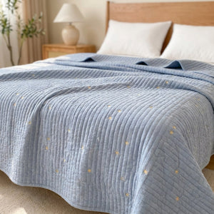 Couvre-lit bleu matelassé brodé d'étoiles dorées sur un lit