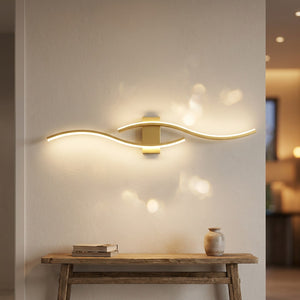 Applique murale dorée double courbe LED 80cm allumée dans une entrée chic
