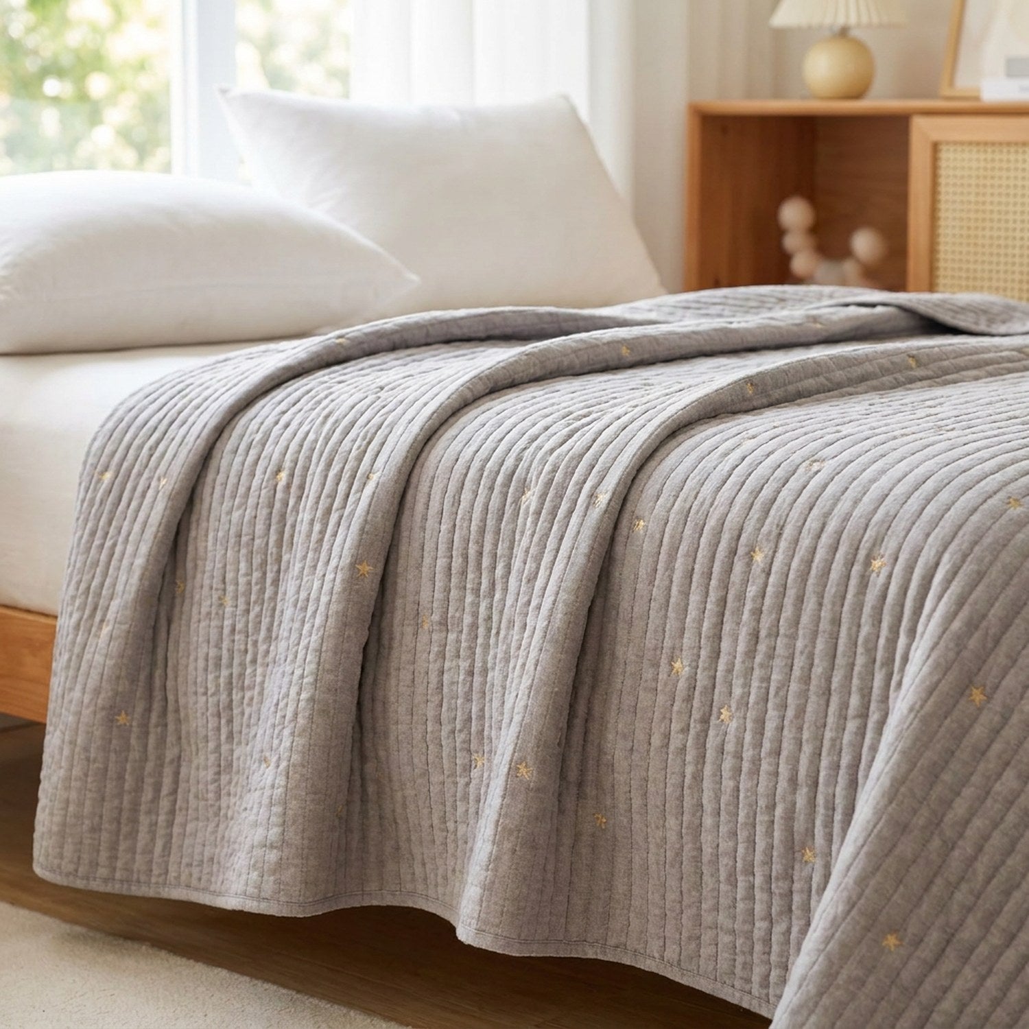 Couvre-lit gris matelassé brodé d'étoiles dorées sur un lit