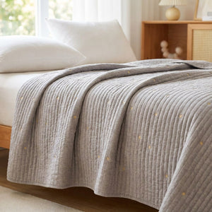 Couvre-lit gris matelassé brodé d'étoiles dorées sur un lit