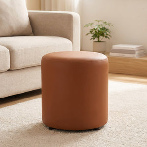 Tabouret pouf rond marron cognac posé sur un tapis dans un salon