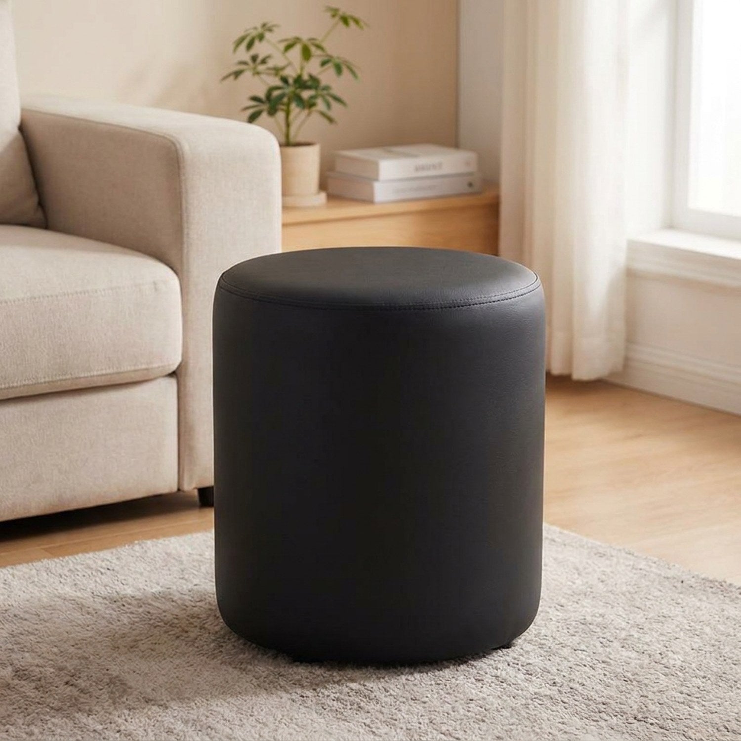 Tabouret pouf rond noir posé sur un tapis dans un salon lumineux
