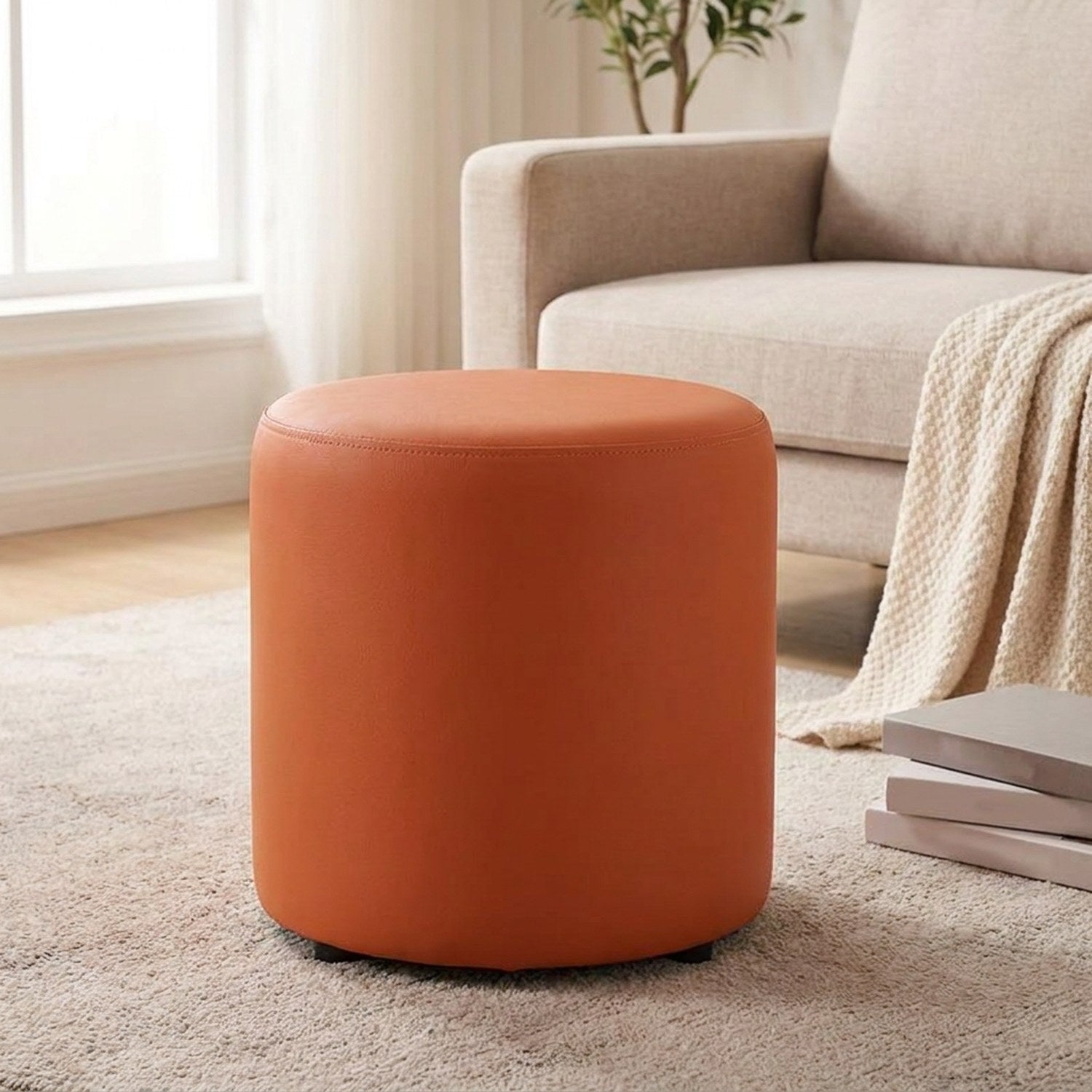 Tabouret pouf rond orange terracotta posé sur un tapis dans un salon
