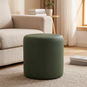 Tabouret pouf rond vert olive posé sur un tapis près d'un canapé