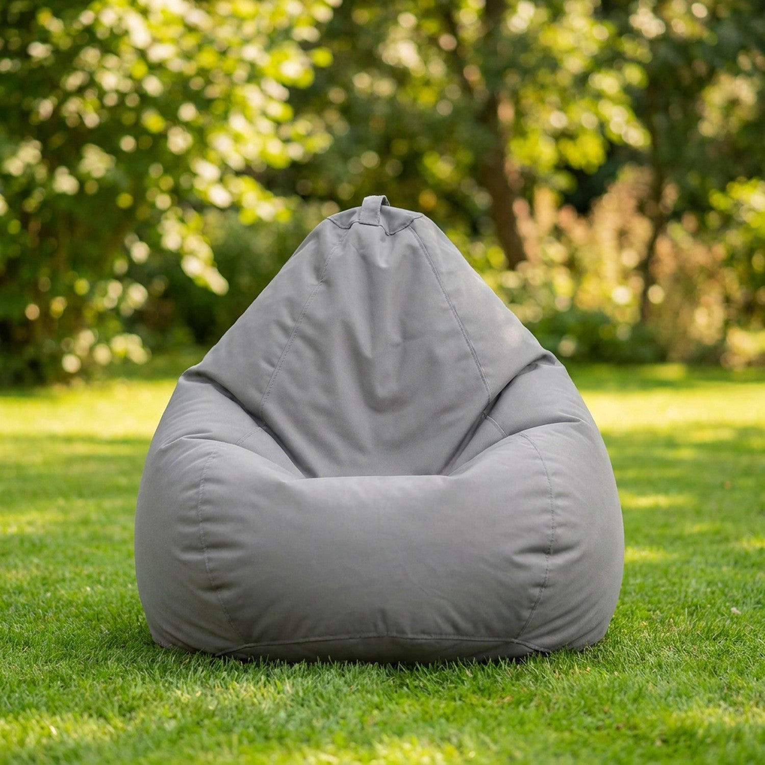 Housse de pouf poire grise posée sur une pelouse verte