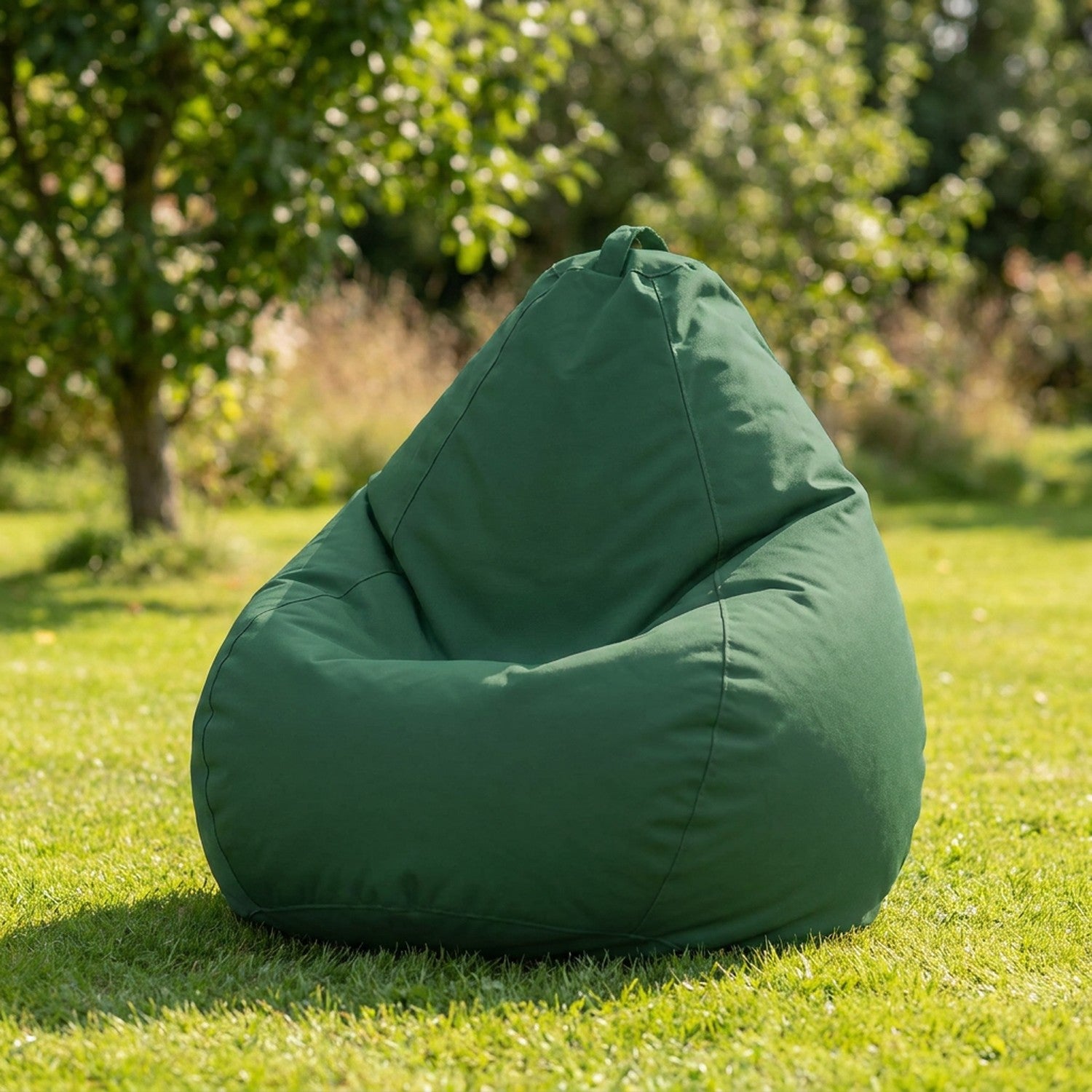 Housse de pouf poire vert foncé sur une pelouse de jardin
