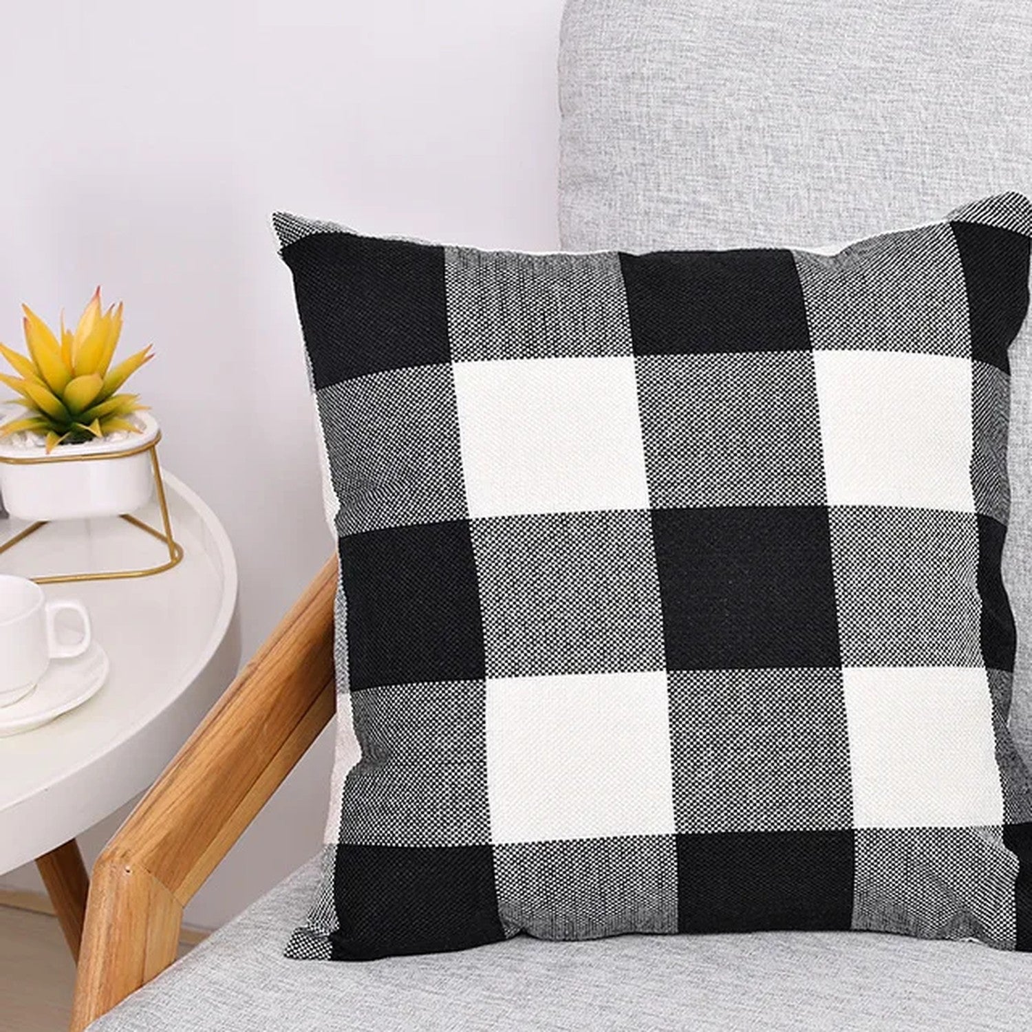 Housse de coussin à carreaux noir et blanc posée sur un canapé clair