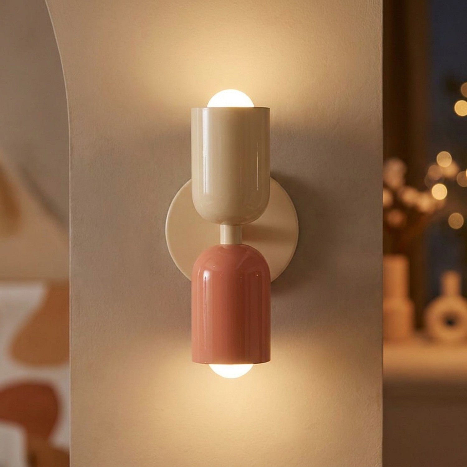 Applique murale LED double tête beige et rose allumée sur un mur clair