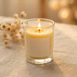 Bougie parfumée jaune en cire de soja allumée sur une nappe en lin