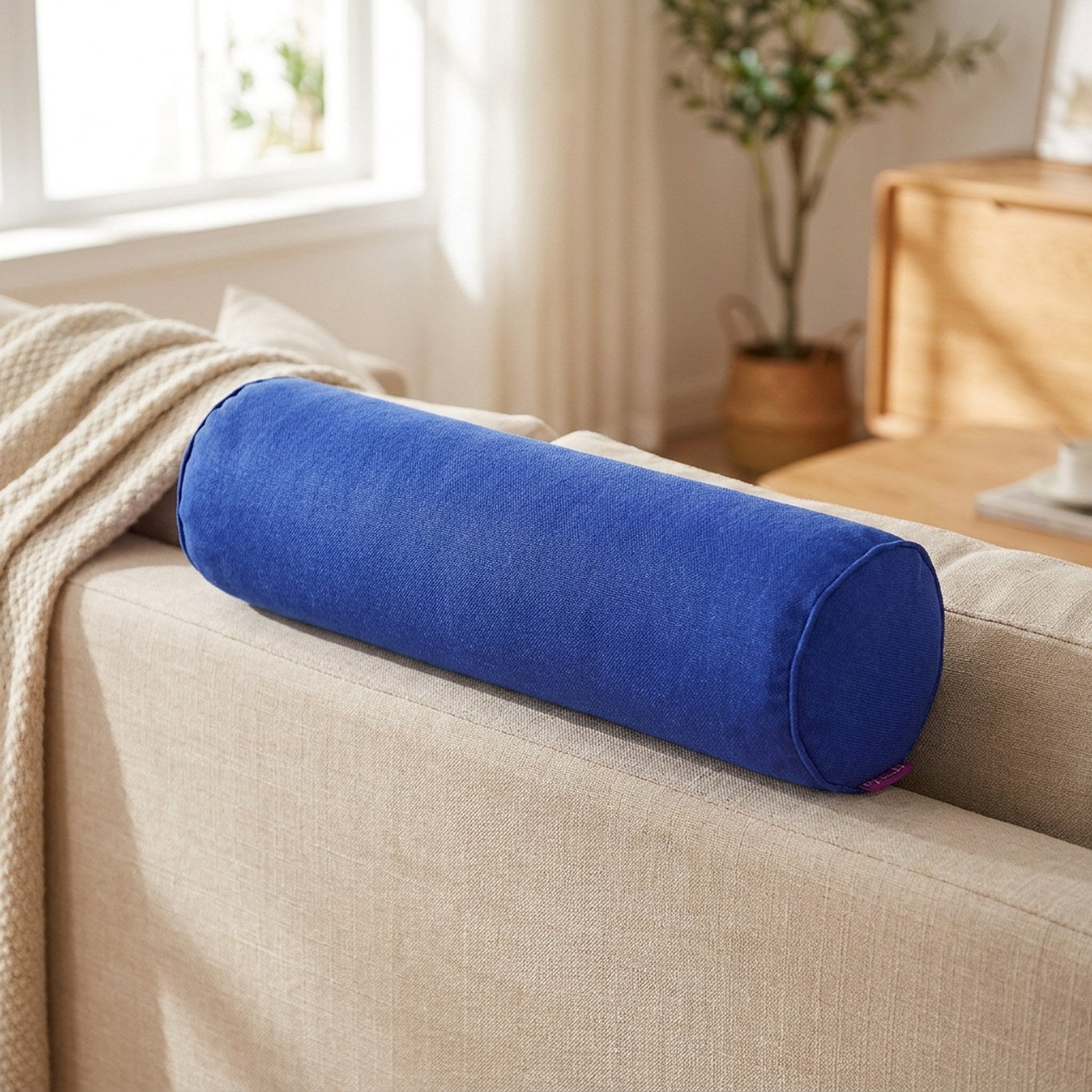 Housse de traversin cylindrique bleu roi sur un canapé en lin beige