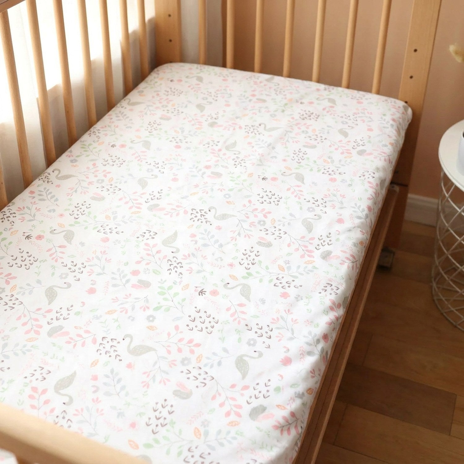 Drap housse bébé motif cygne rose et fleurs sur un matelas de berceau