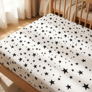 Drap housse bébé motif étoiles noires sur un matelas de berceau