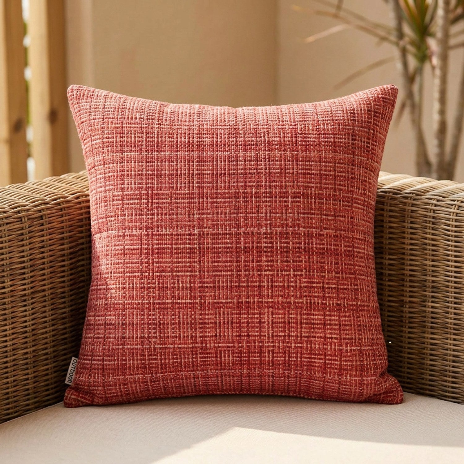Housse de coussin d'extérieur imperméable rouge au tissage texturé sur un canapé en rotin