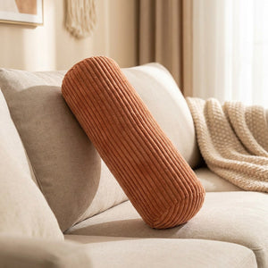 Traversin cylindrique en velours côtelé couleur terracotta sur un canapé beige