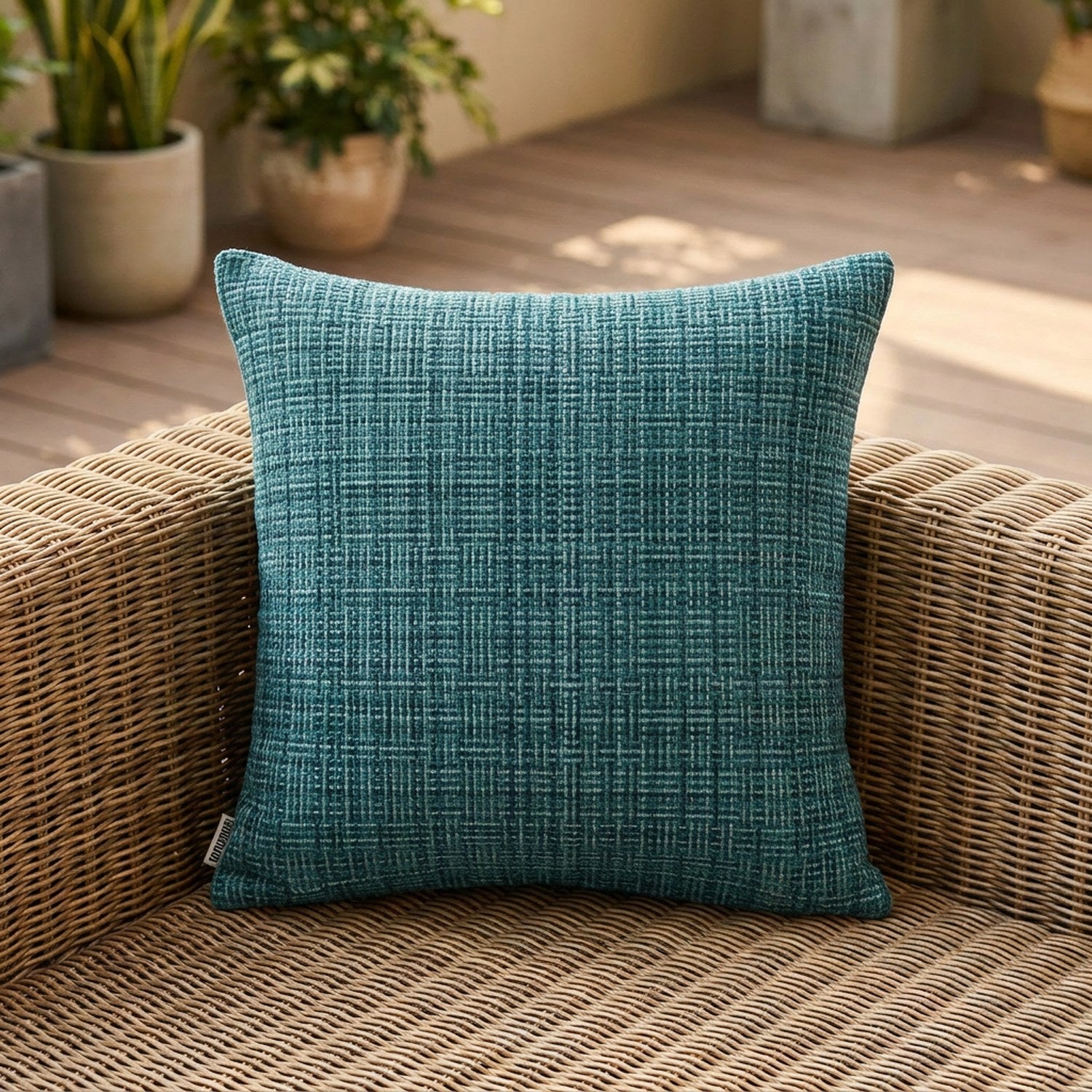 Housse de coussin d'extérieur imperméable turquoise au tissage texturé sur un canapé en rotin