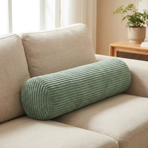 Traversin cylindrique en velours côtelé vert clair sur un canapé beige