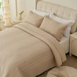 Couvre-lit matelassé beige à fines lignes matelassées installé sur un lit fait