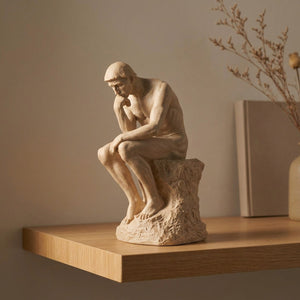 Statue Le Penseur de Rodin en résine beige sur une étagère en bois