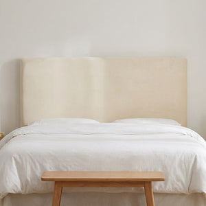 Housse de tête de lit en velours beige vue de face sur un lit