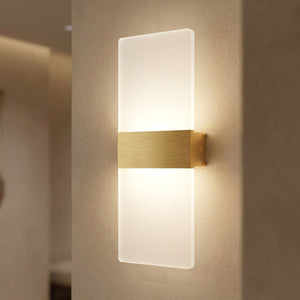 Applique murale LED dorée allumée sur un mur clair