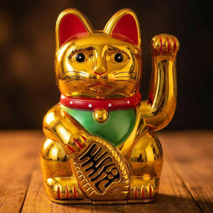Figurine chat porte-bonheur doré brillant posé sur une surface en bois sombre
