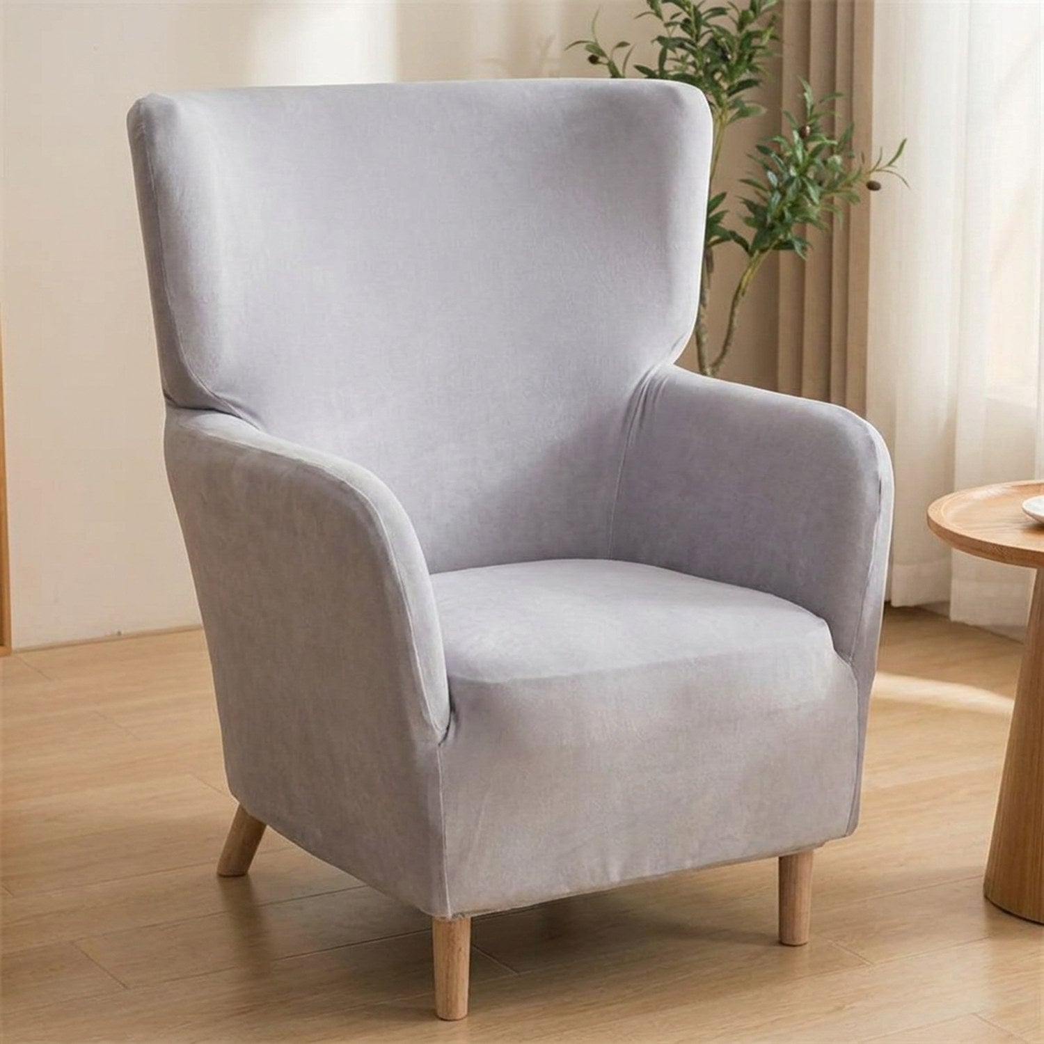 Housse de fauteuil à oreilles en velours gris clair sur un fauteuil une place
