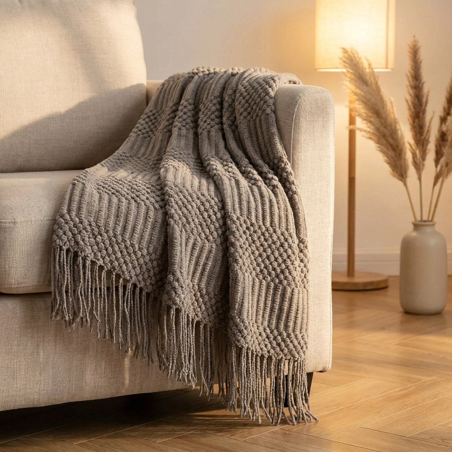 Plaid tricoté gris à franges drapé sur un fauteuil