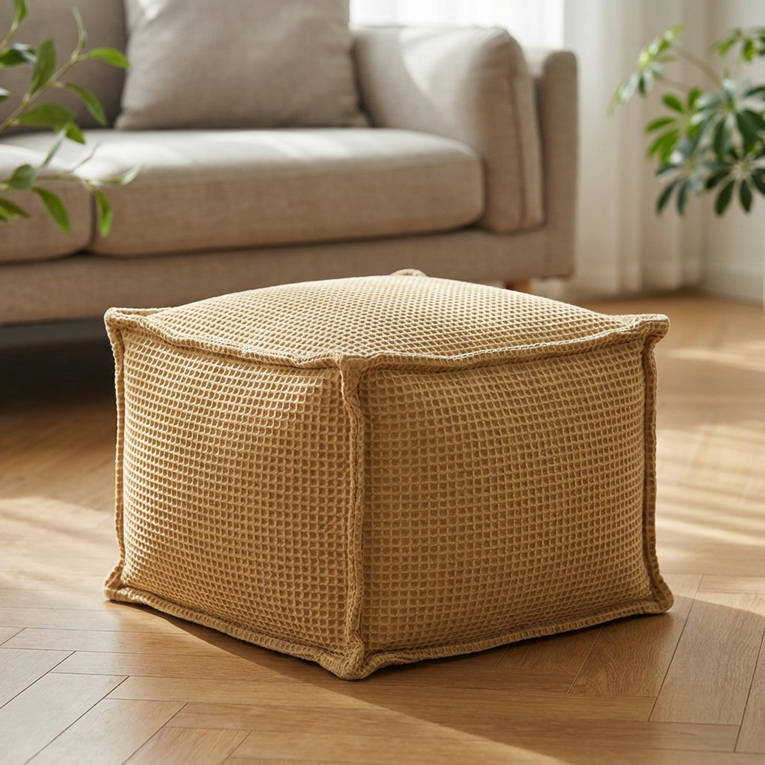 Pouf carré en coton gaufré kaki posé au sol dans un salon lumineux près d'un canapé