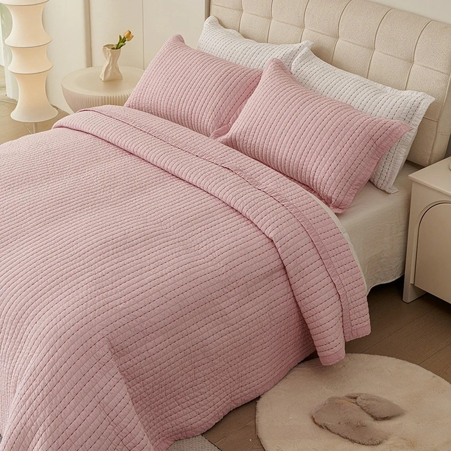 Couvre-lit matelassé rose à fines lignes matelassées installé sur un lit fait