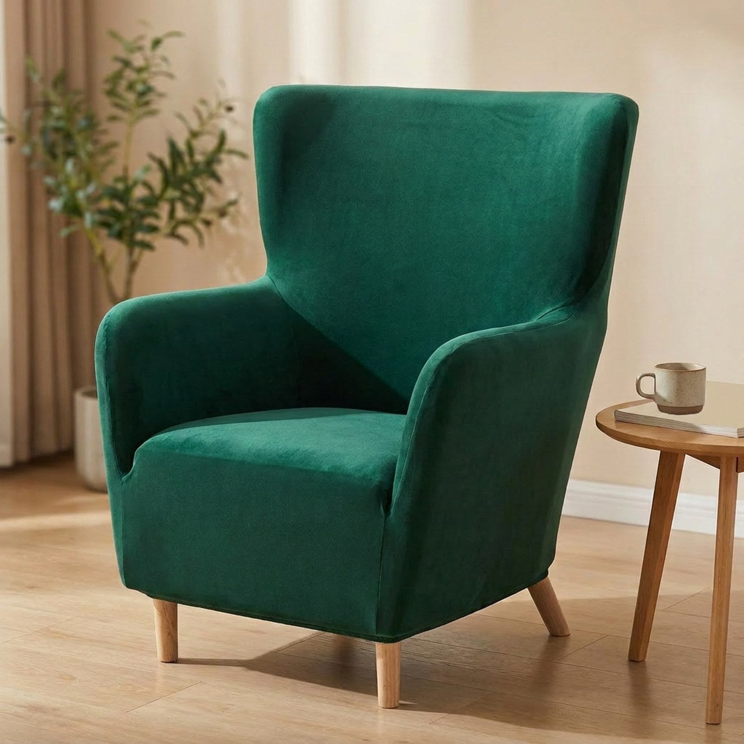 Housse de fauteuil à oreilles en velours vert émeraude installée sur un fauteuil dans un salon lumineux