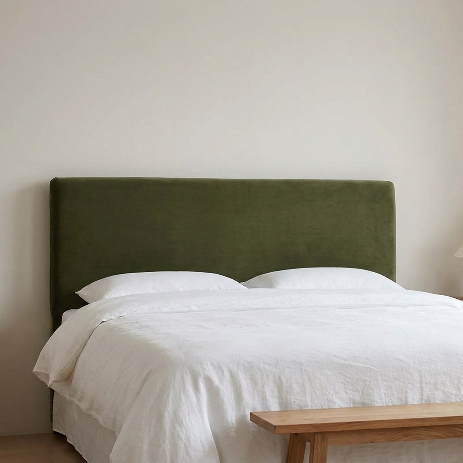 Housse de tête de lit en velours vert foncé vue de face sur un lit