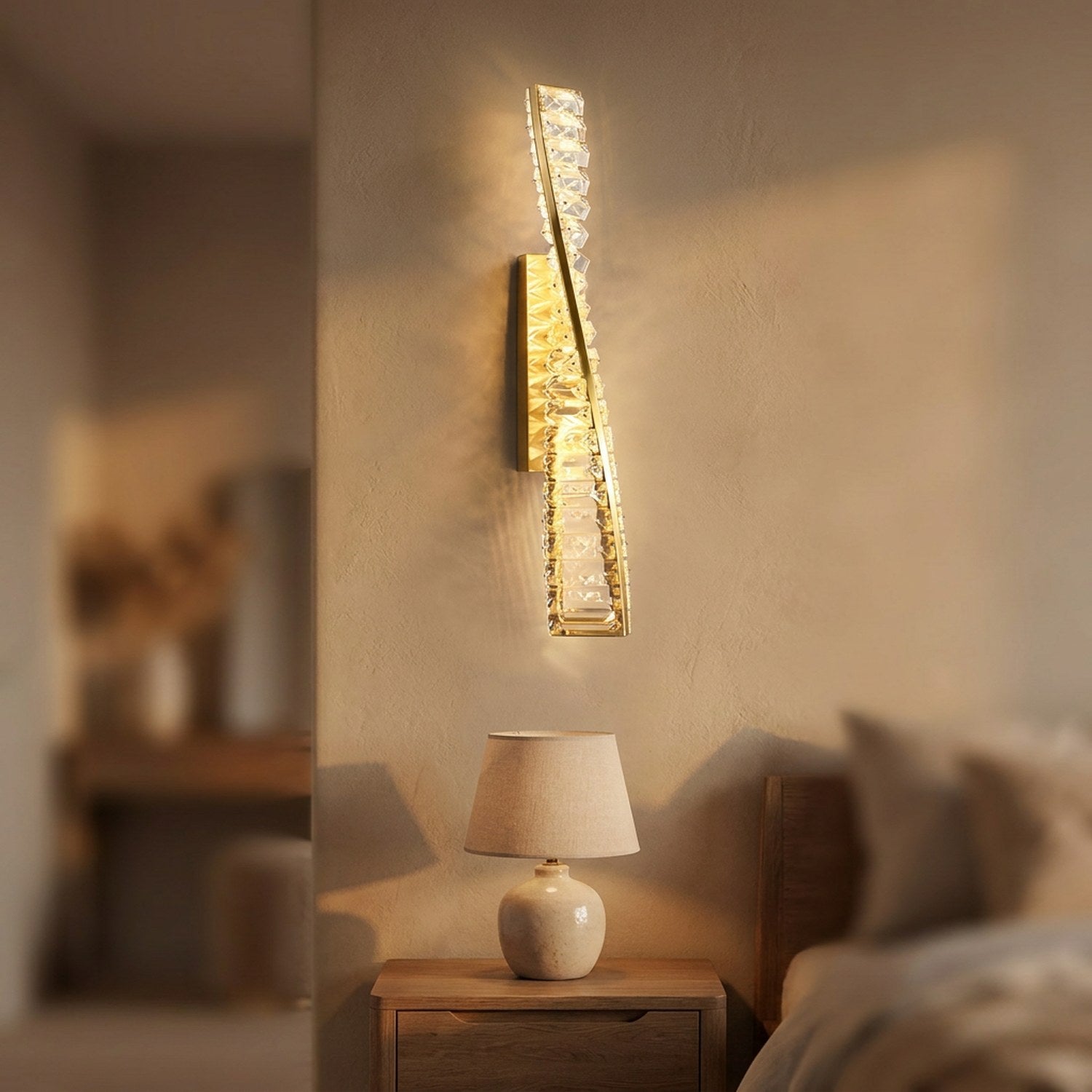Applique murale en cristal doré hauteur 50 cm allumée au-dessus d'une table de chevet