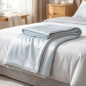 Couette d'été en soie glacée coloris bleu pliée sur un lit
