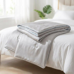 Couette d'été en soie glacée coloris gris pliée sur un lit