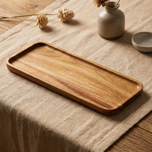 Plateau rectangulaire allongé en bois d'acacia posé sur une nappe en lin beige