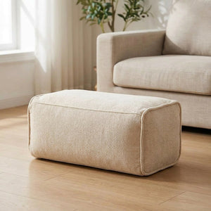 Pouf repose-pieds rectangulaire en chenille beige posé dans un salon lumineux et chaleureux