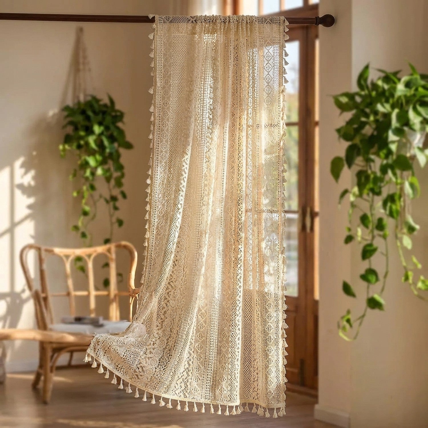 Rideau boho en dentelle au crochet beige à pompons suspendu devant une fenêtre lumineuse