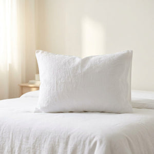 Taie d'oreiller en lin lavé blanc sur un lit dans une chambre épurée