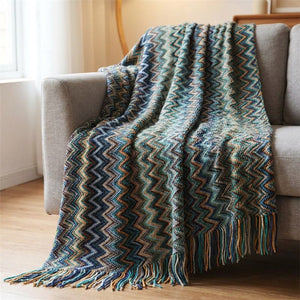 Plaid tricoté chevrons coloris bleu drapé sur un fauteuil gris