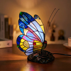 Lampe style Tiffany papillon en vitrail bleu allumée sur une surface en bois