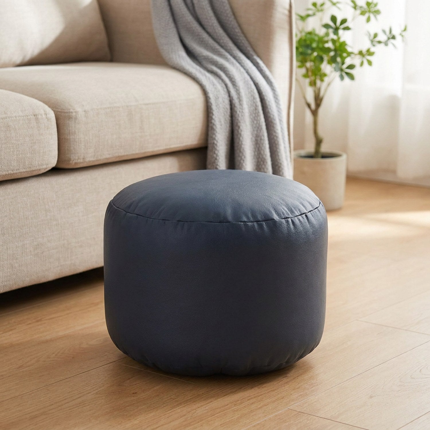 Pouf marocain rond en simili cuir bleu marine posé sur un parquet clair
