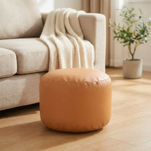 Pouf marocain rond en simili cuir caramel posé sur un parquet chaleureux