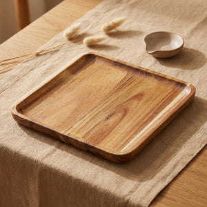 Plateau carré en bois d'acacia posé sur une nappe en lin beige