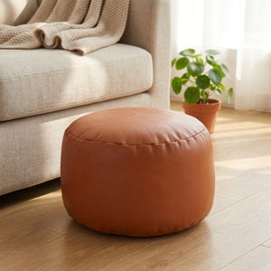 Pouf marocain rond en simili cuir cognac posé sur un parquet dans un salon chaleureux