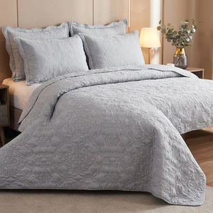 Couvre-lit matelassé gris perle avec deux taies assorties sur un lit