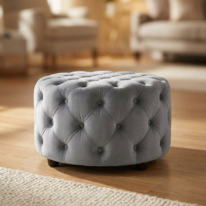 Tabouret pouf rond en velours gris capitonné sur parquet