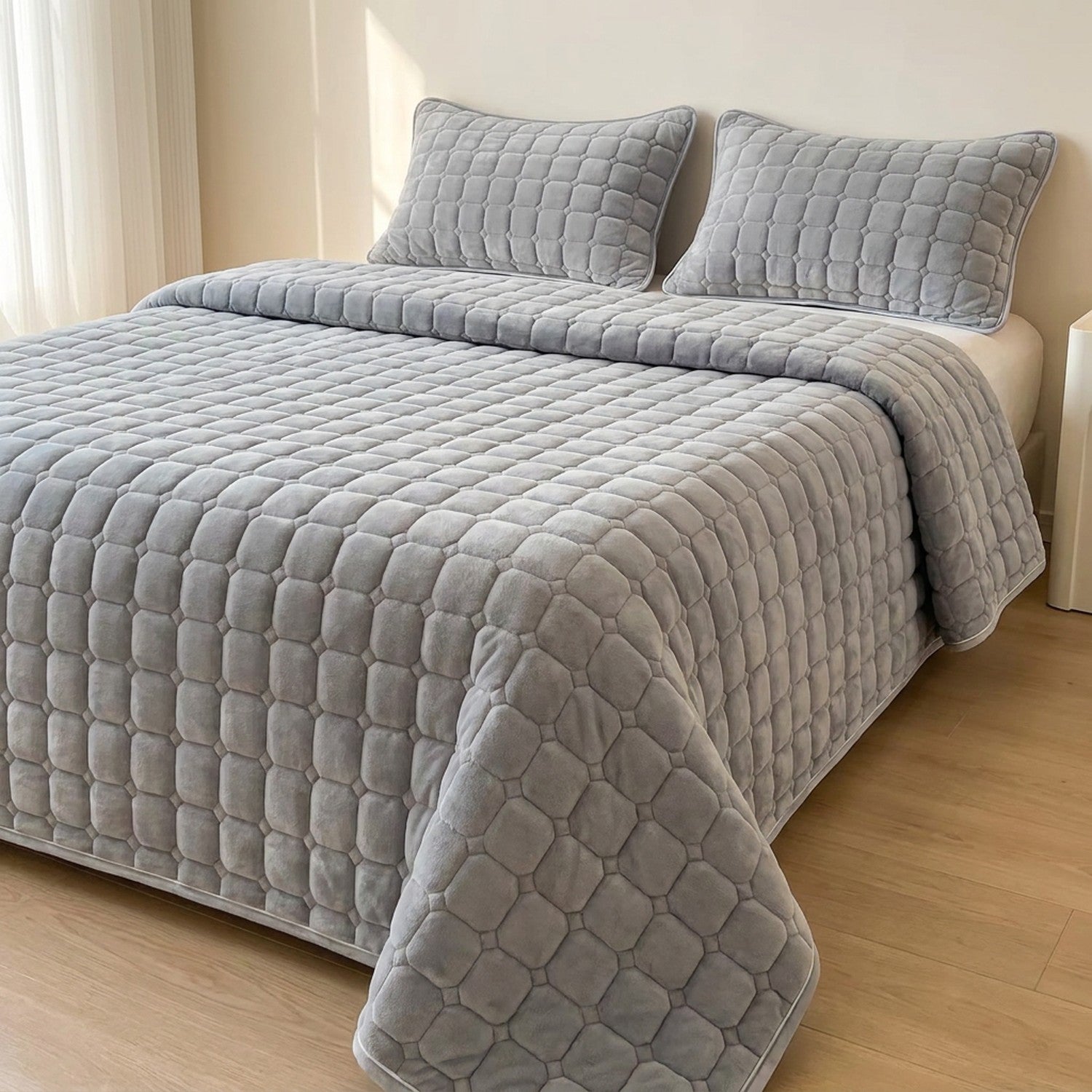 Couvre-lit matelassé velours gris clair avec deux taies assorties sur un lit