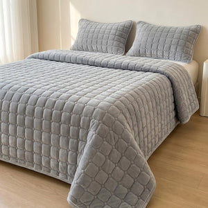 Couvre-lit matelassé velours gris clair avec deux taies assorties sur un lit