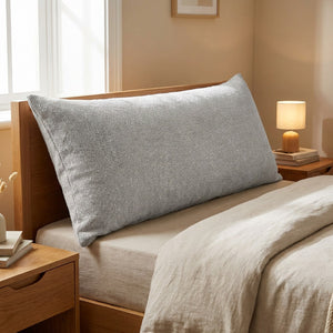 Housse de coussin longue en coton et lin gris clair sur une tête de lit